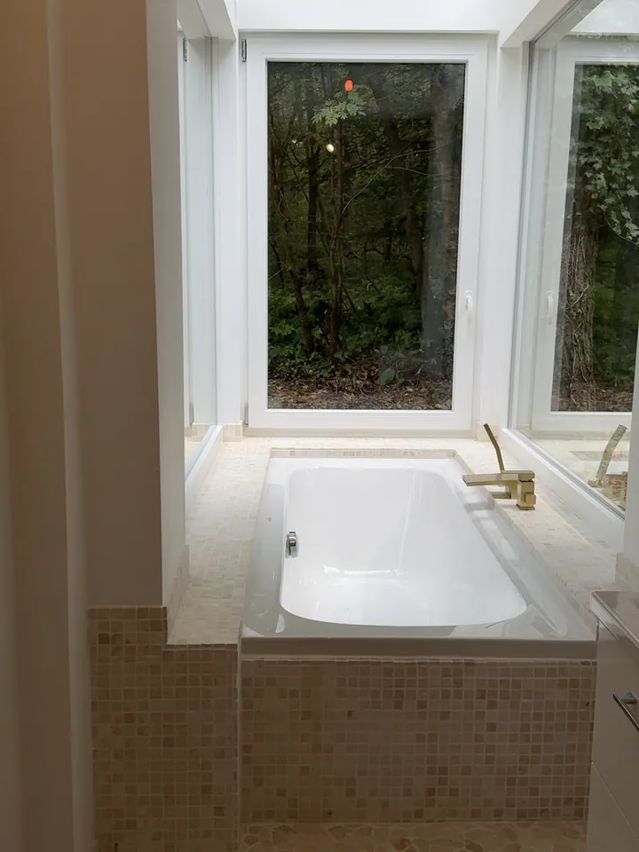 Sauberes Bad mit Badewanne und Fenster zum Garten